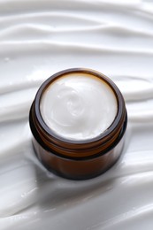 Photo of Face cream in jar on cosmetic product, closeup