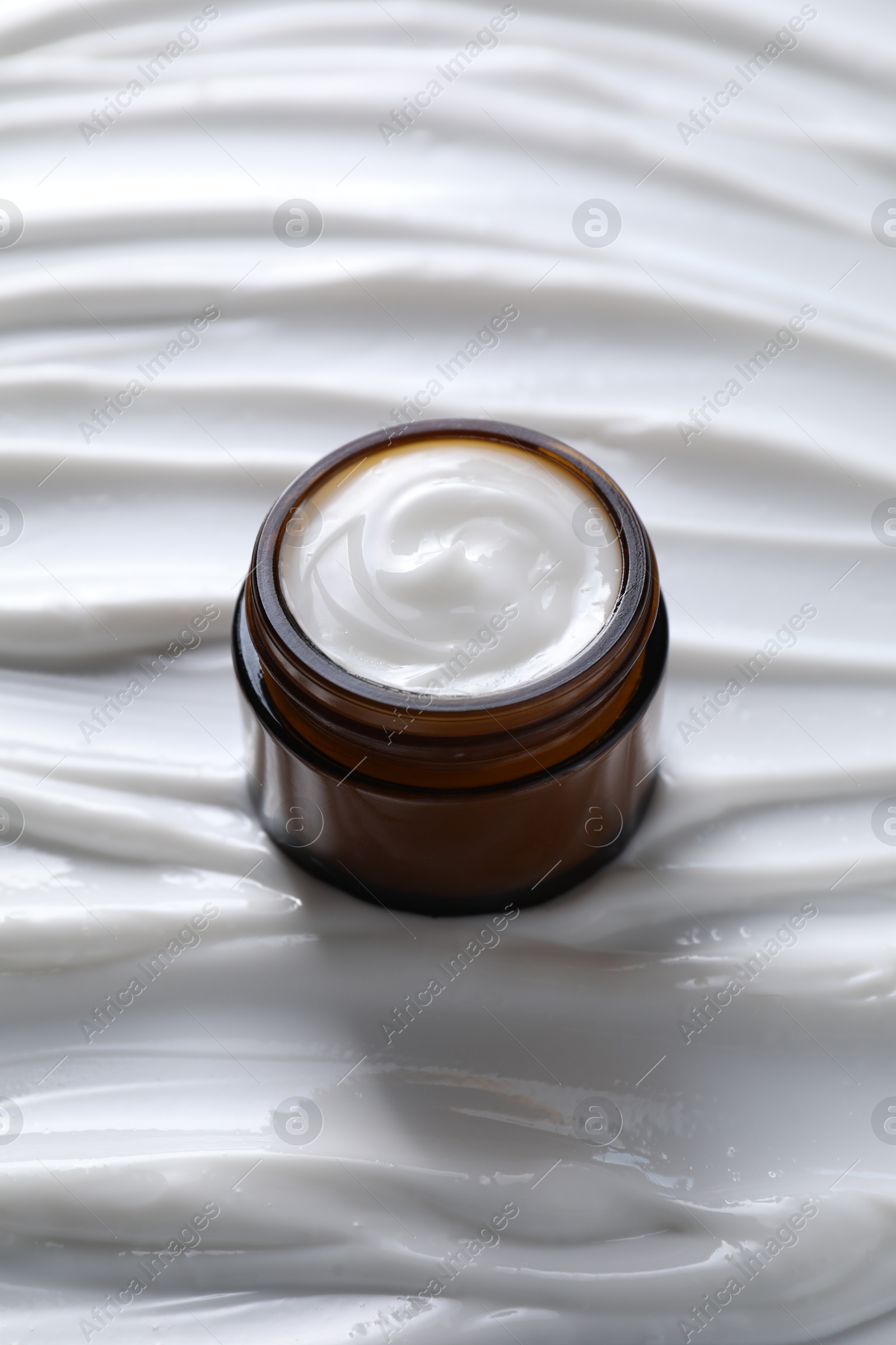 Photo of Face cream in jar on cosmetic product, closeup