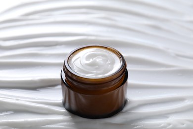 Photo of Face cream in jar on cosmetic product, closeup