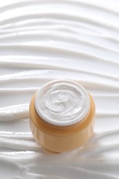 Photo of Face cream in jar on cosmetic product, above view