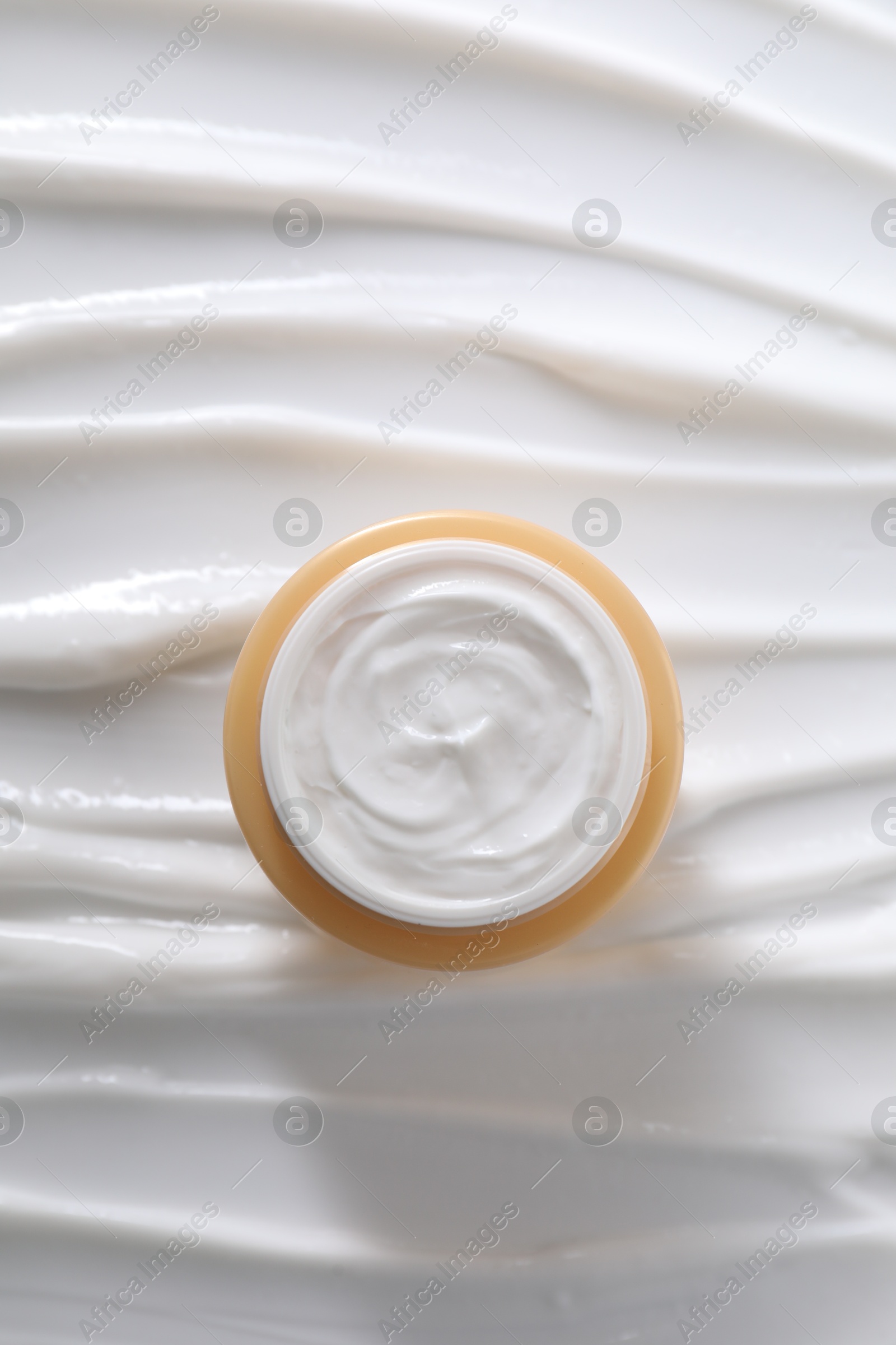 Photo of Face cream in jar on cosmetic product, top view