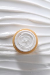 Face cream in jar on cosmetic product, top view