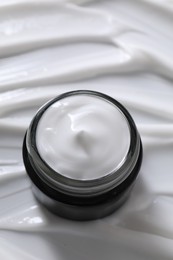 Face cream in jar on cosmetic product, above view