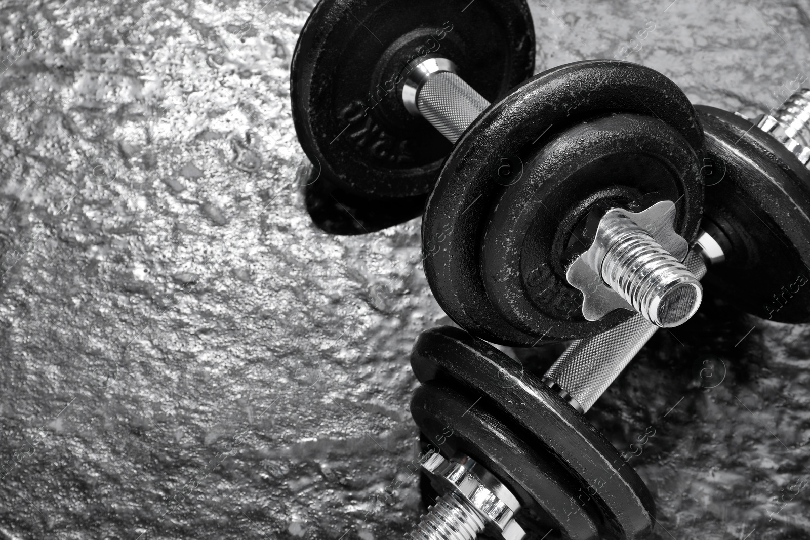 Photo of Barbells on dark textured floor, closeup. Space for text