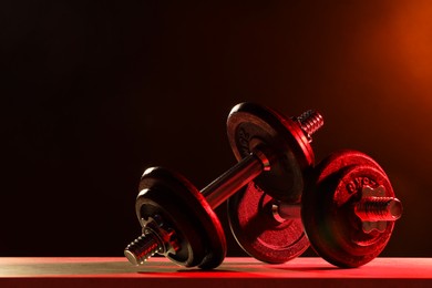 Photo of Two barbells on table in color lights. Space for text