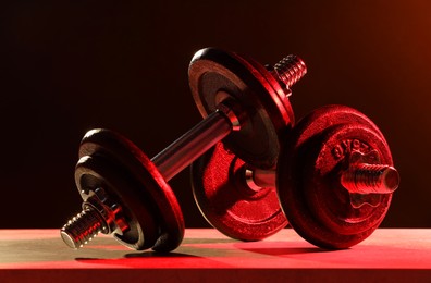 Photo of Two barbells on table in color lights, closeup