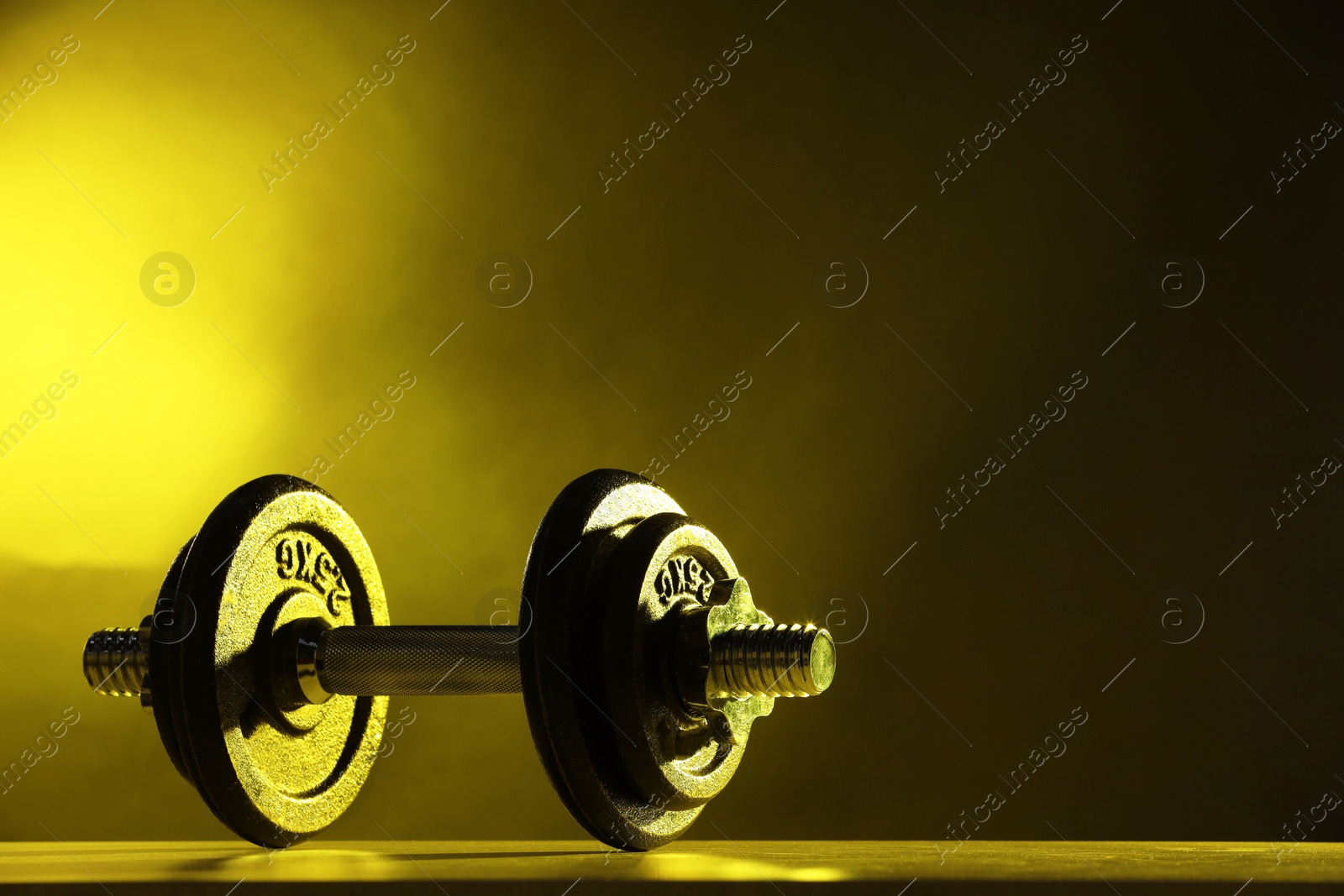 Photo of Barbell on table in color lights. Space for text