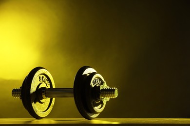 Photo of Barbell on table in color lights. Space for text