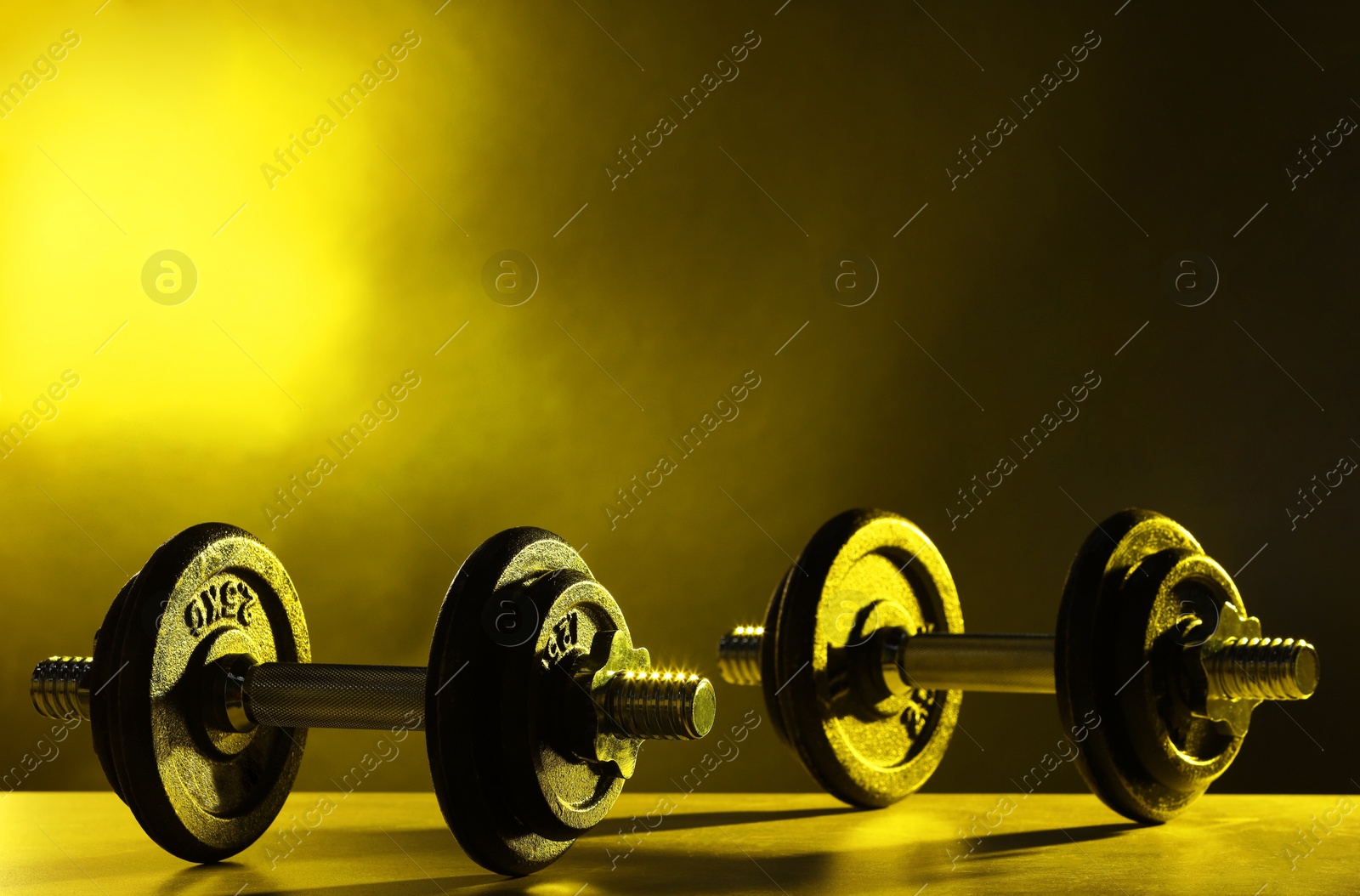 Photo of Two barbells on table in color lights. Space for text