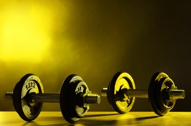 Photo of Two barbells on table in color lights. Space for text