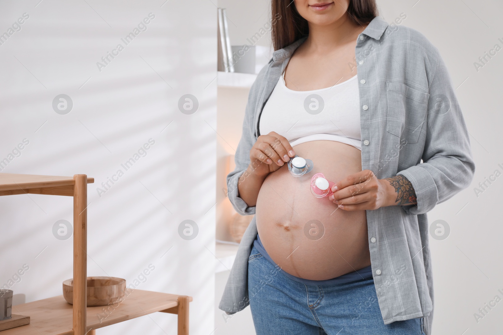 Photo of Pregnant woman with pacifiers at home, closeup. Expecting twins