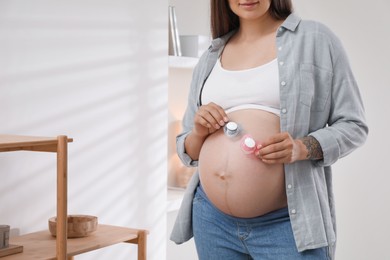 Photo of Pregnant woman with pacifiers at home, closeup. Expecting twins