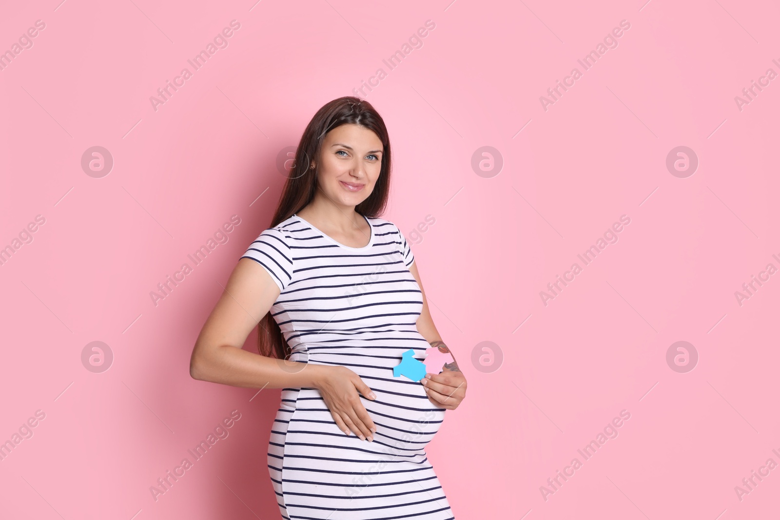 Photo of Beautiful pregnant woman with paper hearts on pink background. Expecting twins