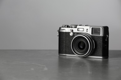 Vintage photo camera on grey marble table, space for text