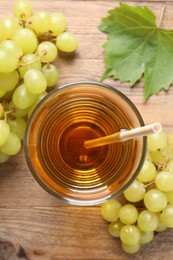 Tasty juice in glass, fresh grapes and leaf on wooden table, top view