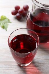 Tasty grape juice and berries on light wooden table, closeup