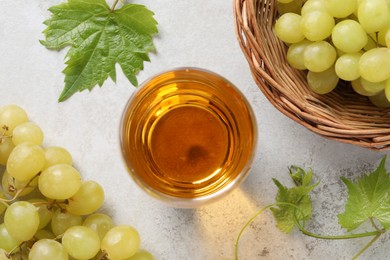 Tasty grape juice in glass, leaves and berries on light textured table, flat lay