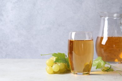 Tasty grape juice, leaves and berries on light table, closeup. Space for text