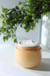 Facial cream in jar and floral decor on table