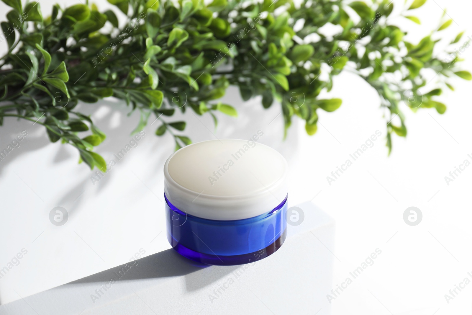 Photo of Facial cream in jar and floral decor on white background