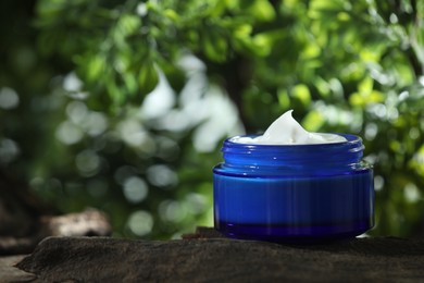 Photo of Stylish presentation of facial cream in jar outdoors, closeup. Space for text