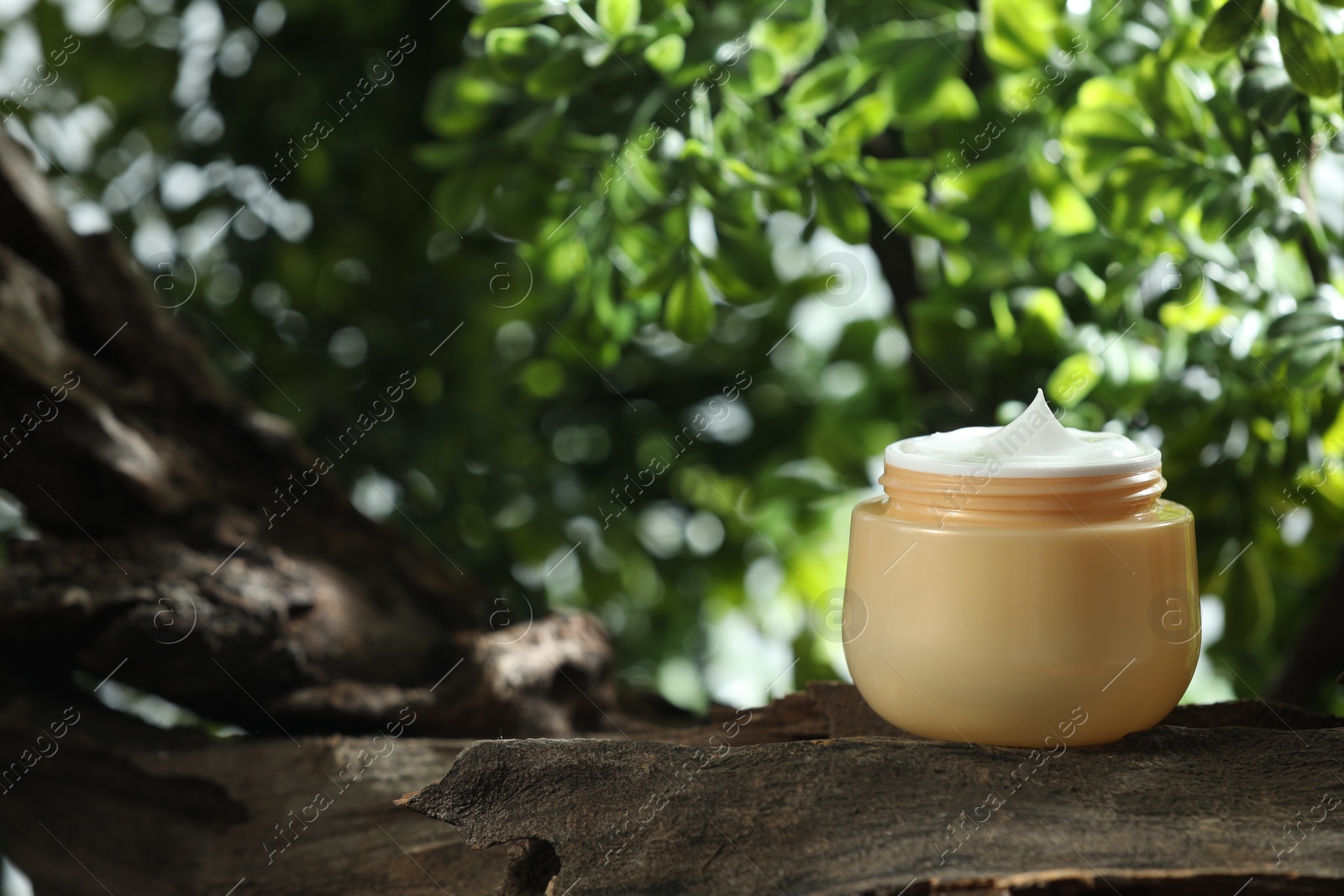 Photo of Stylish presentation of facial cream in jar outdoors, closeup. Space for text