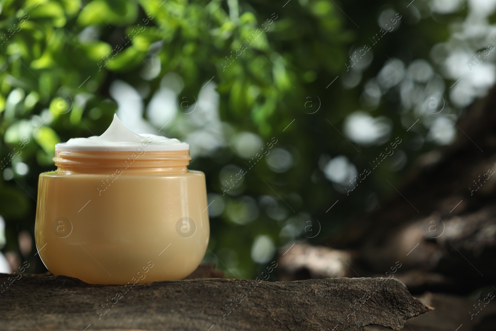 Photo of Stylish presentation of facial cream in jar outdoors, closeup. Space for text