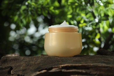 Photo of Stylish presentation of facial cream in jar outdoors, closeup