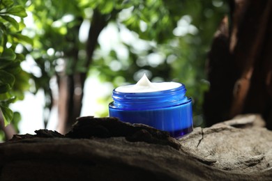 Photo of Stylish presentation of facial cream in jar outdoors, closeup