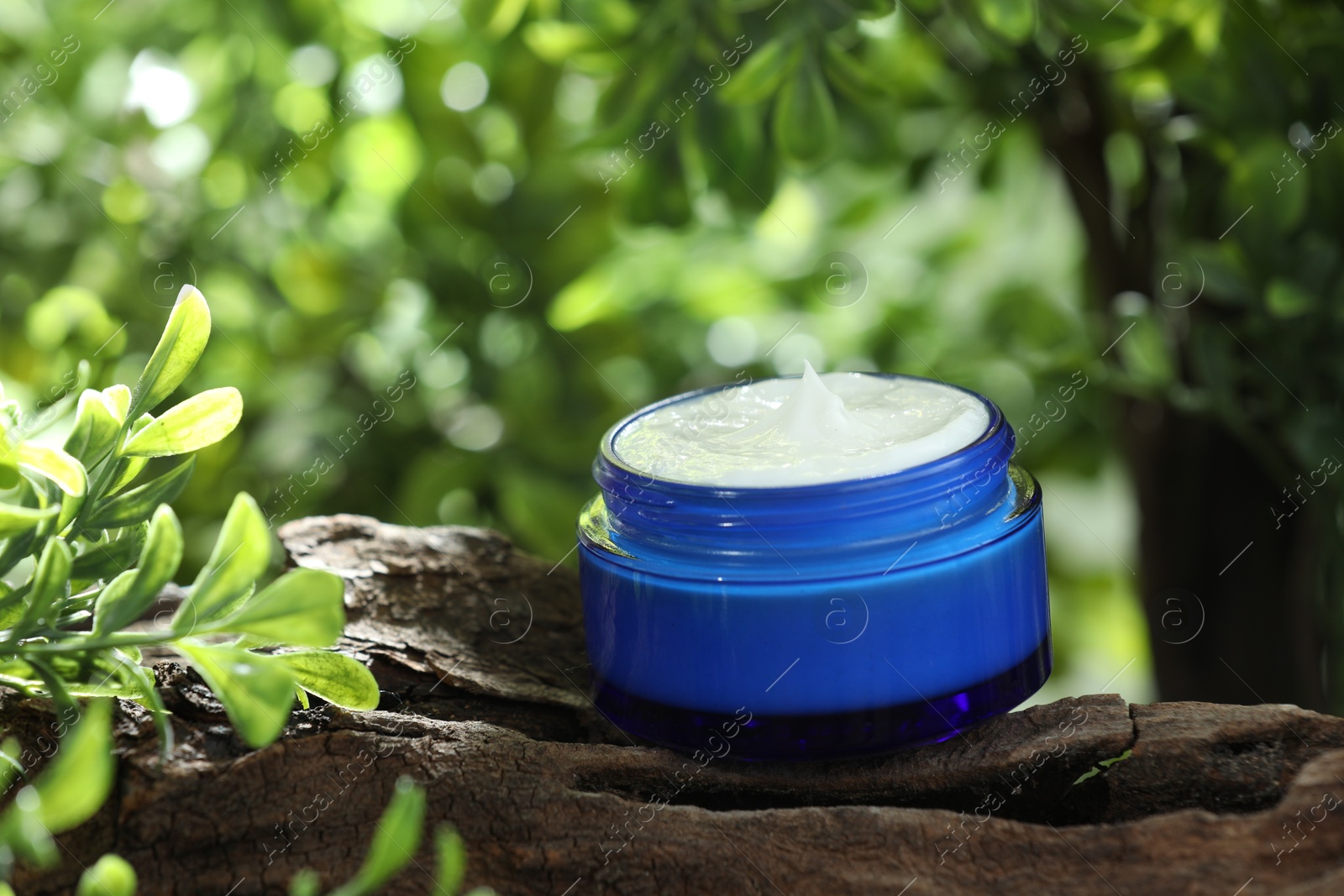 Photo of Stylish presentation of facial cream in jar outdoors, closeup