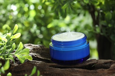 Photo of Stylish presentation of facial cream in jar outdoors, closeup