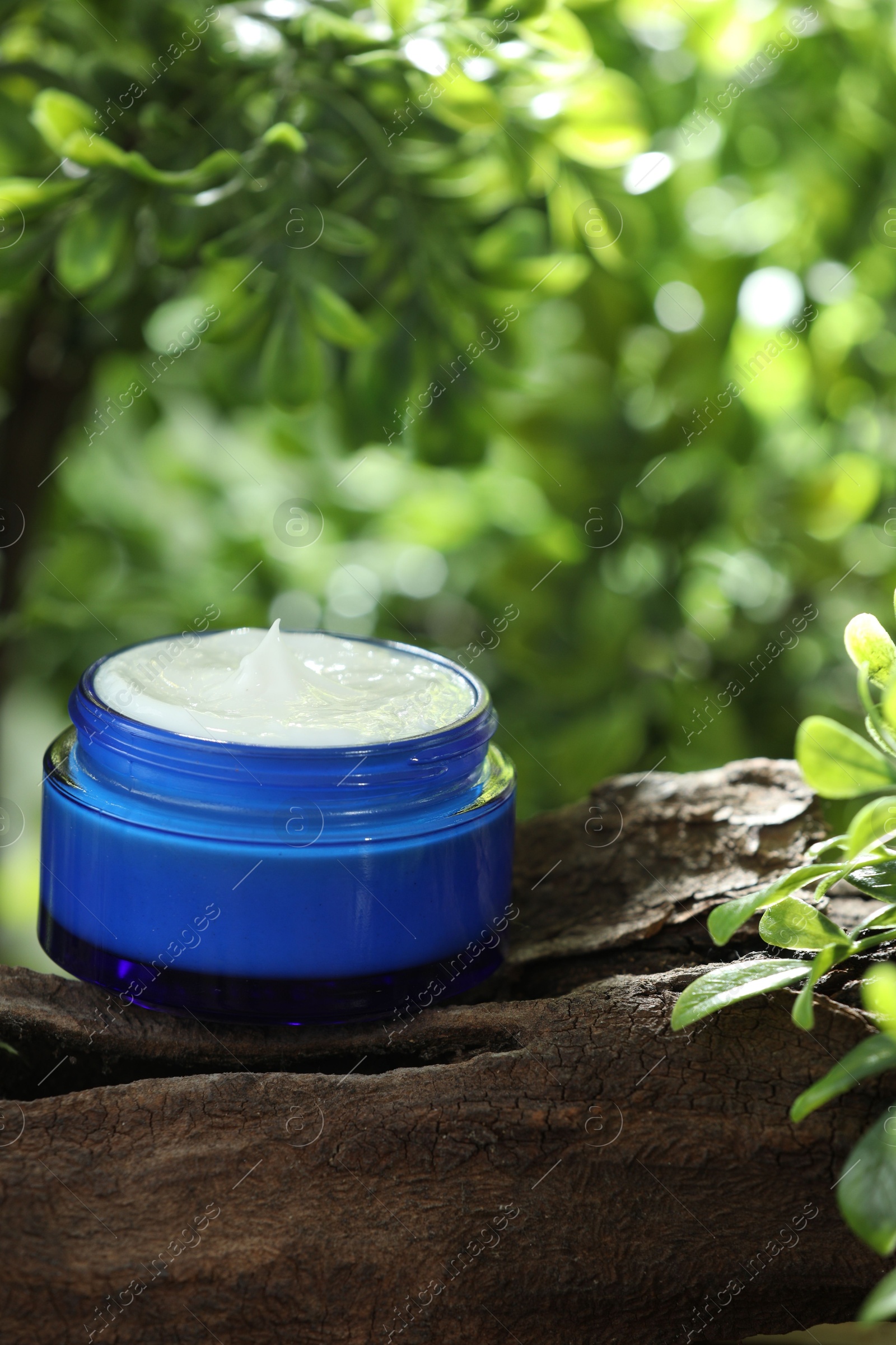 Photo of Stylish presentation of facial cream in jar outdoors, closeup