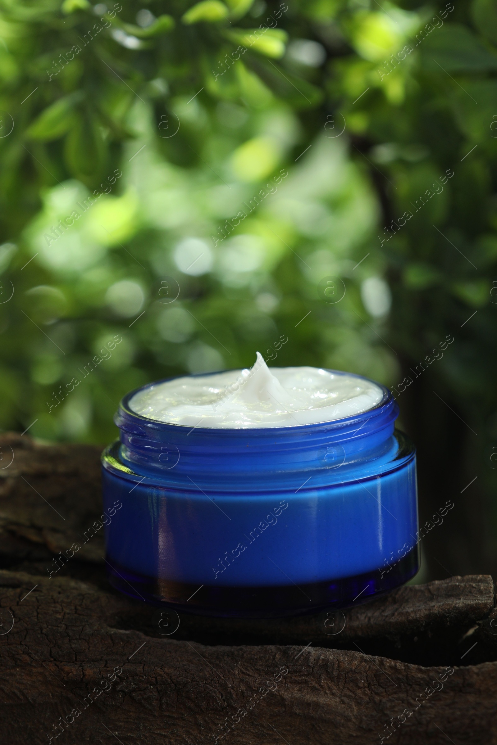 Photo of Stylish presentation of facial cream in jar outdoors, closeup