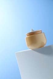 Photo of Face cream in jar against light blue background