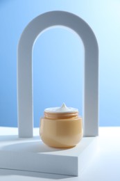 Photo of Stylish presentation of face cream in jar against light blue background