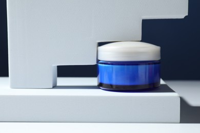 Photo of Stylish presentation of face cream in jar against blue background