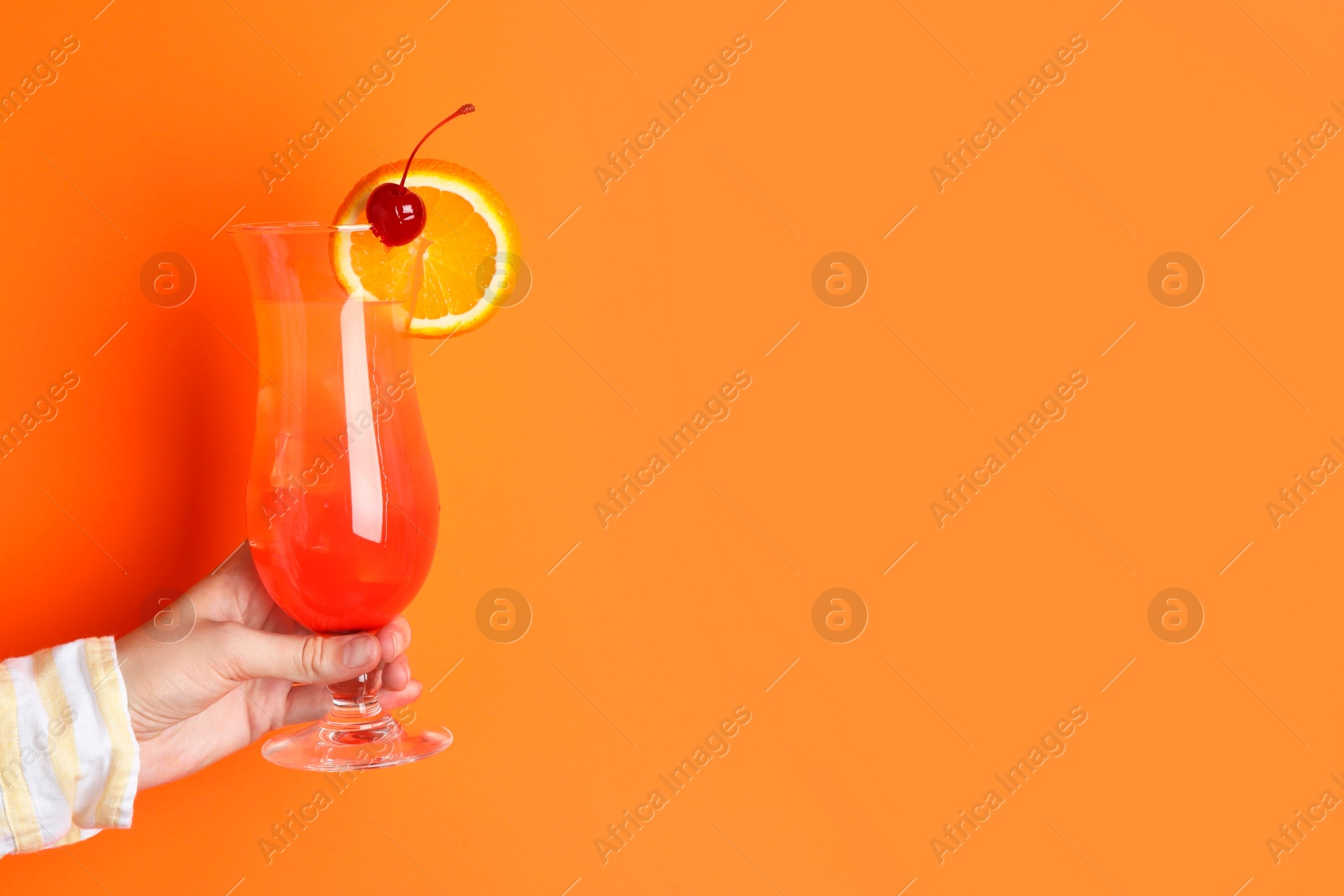 Photo of Woman with glass of refreshing cocktail on orange background, closeup. Space for text