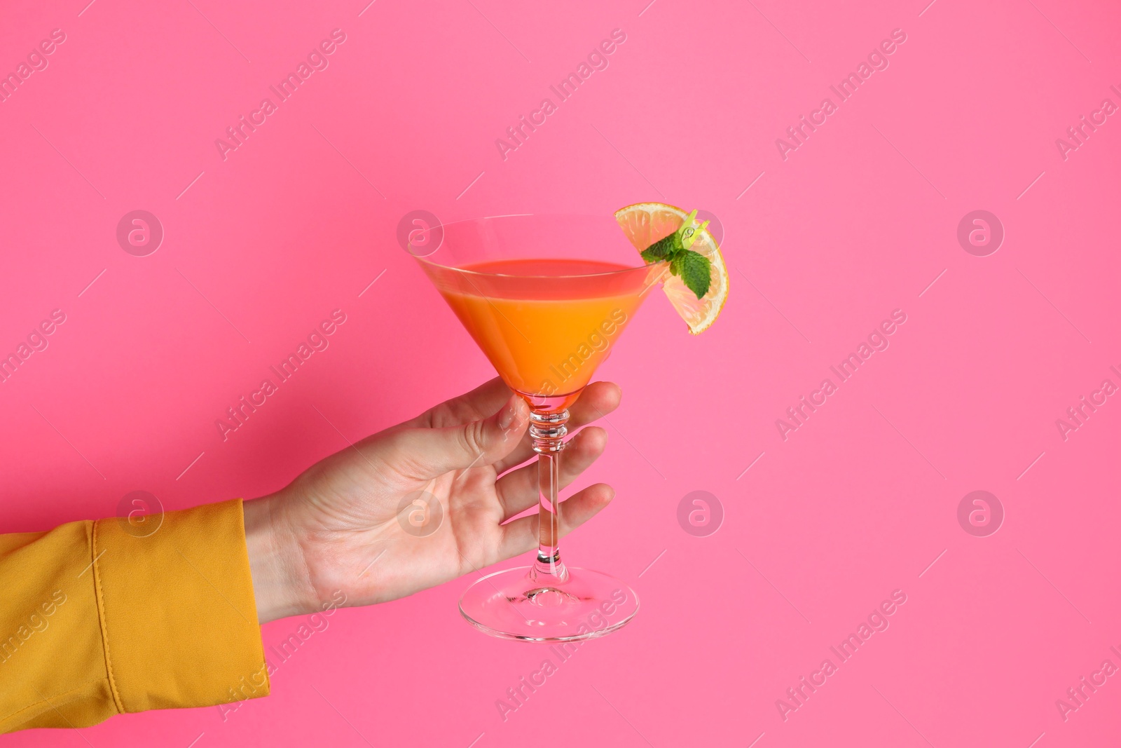 Photo of Woman with glass of refreshing cocktail on pink background, closeup