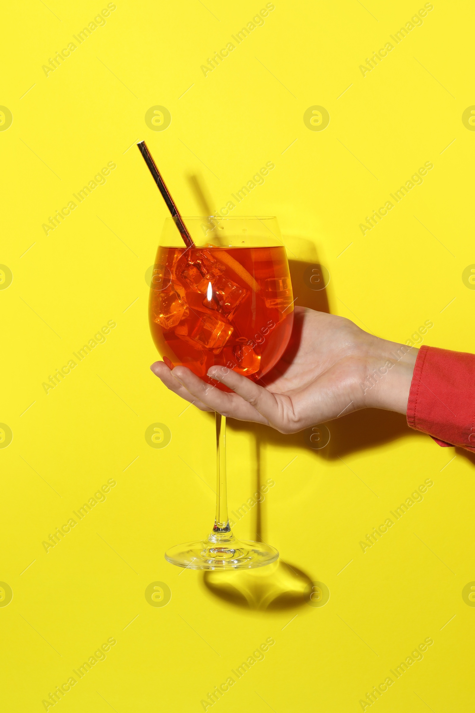 Photo of Woman with glass of refreshing cocktail on yellow background, closeup