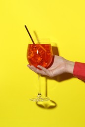 Photo of Woman with glass of refreshing cocktail on yellow background, closeup