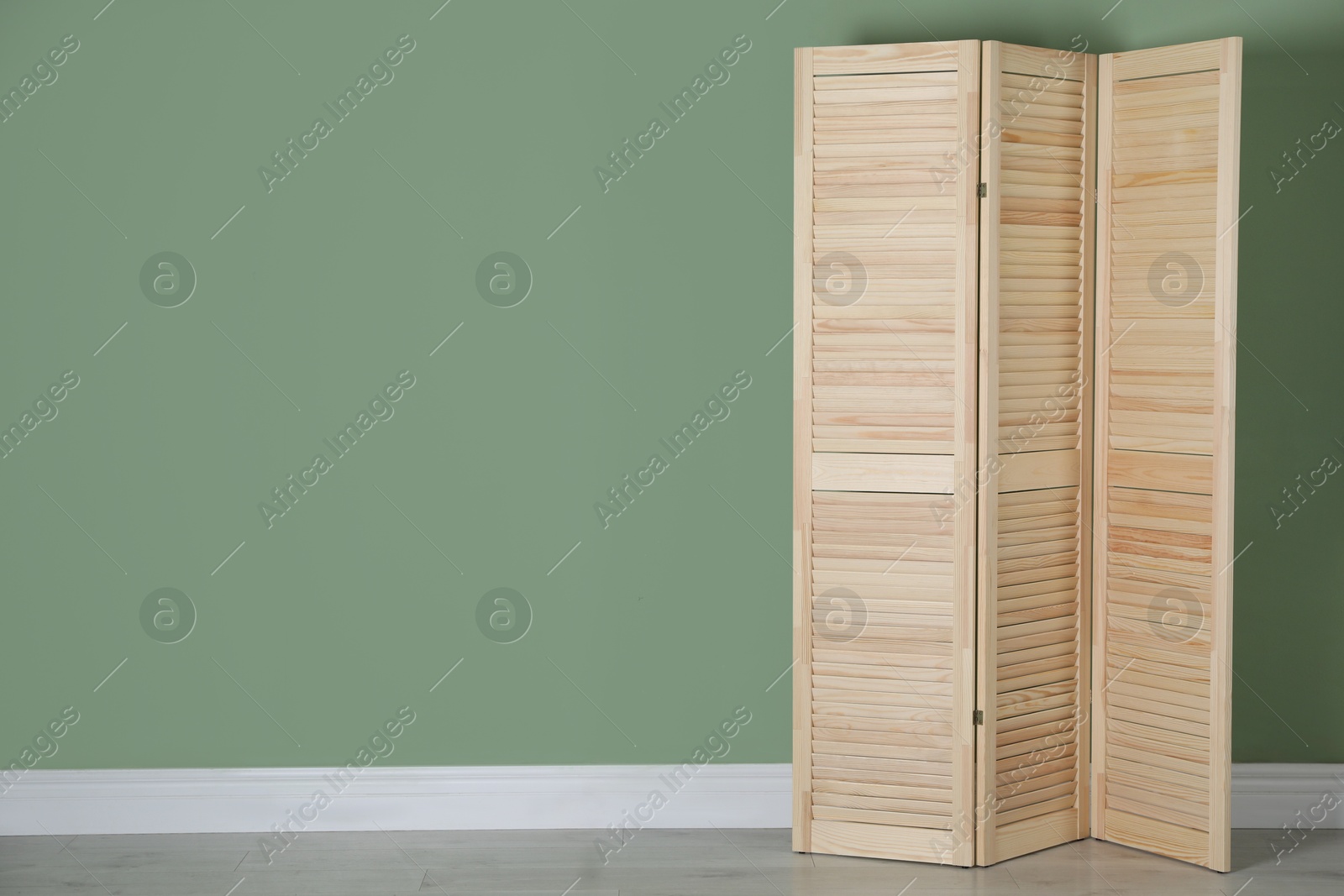 Photo of Wooden folding screen near green wall indoors, space for text