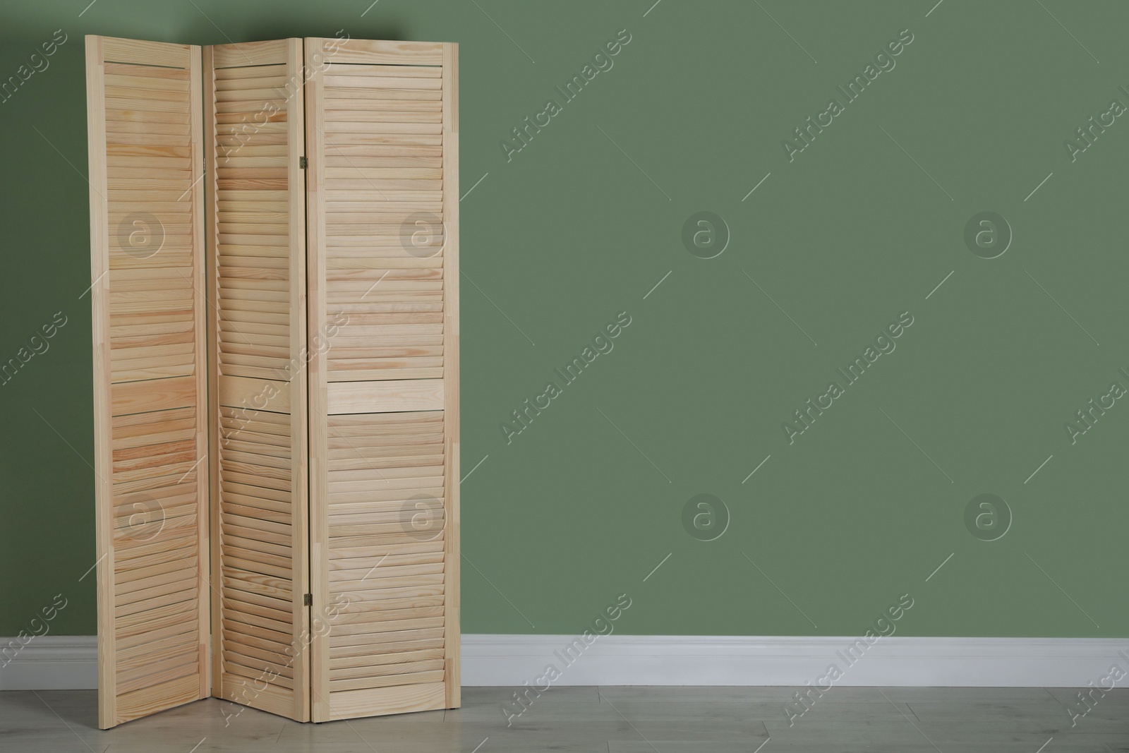 Photo of Wooden folding screen near green wall indoors, space for text