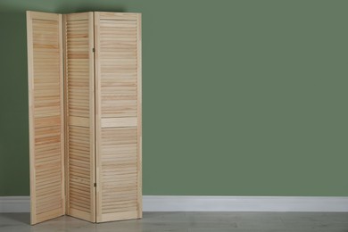 Wooden folding screen near green wall indoors, space for text