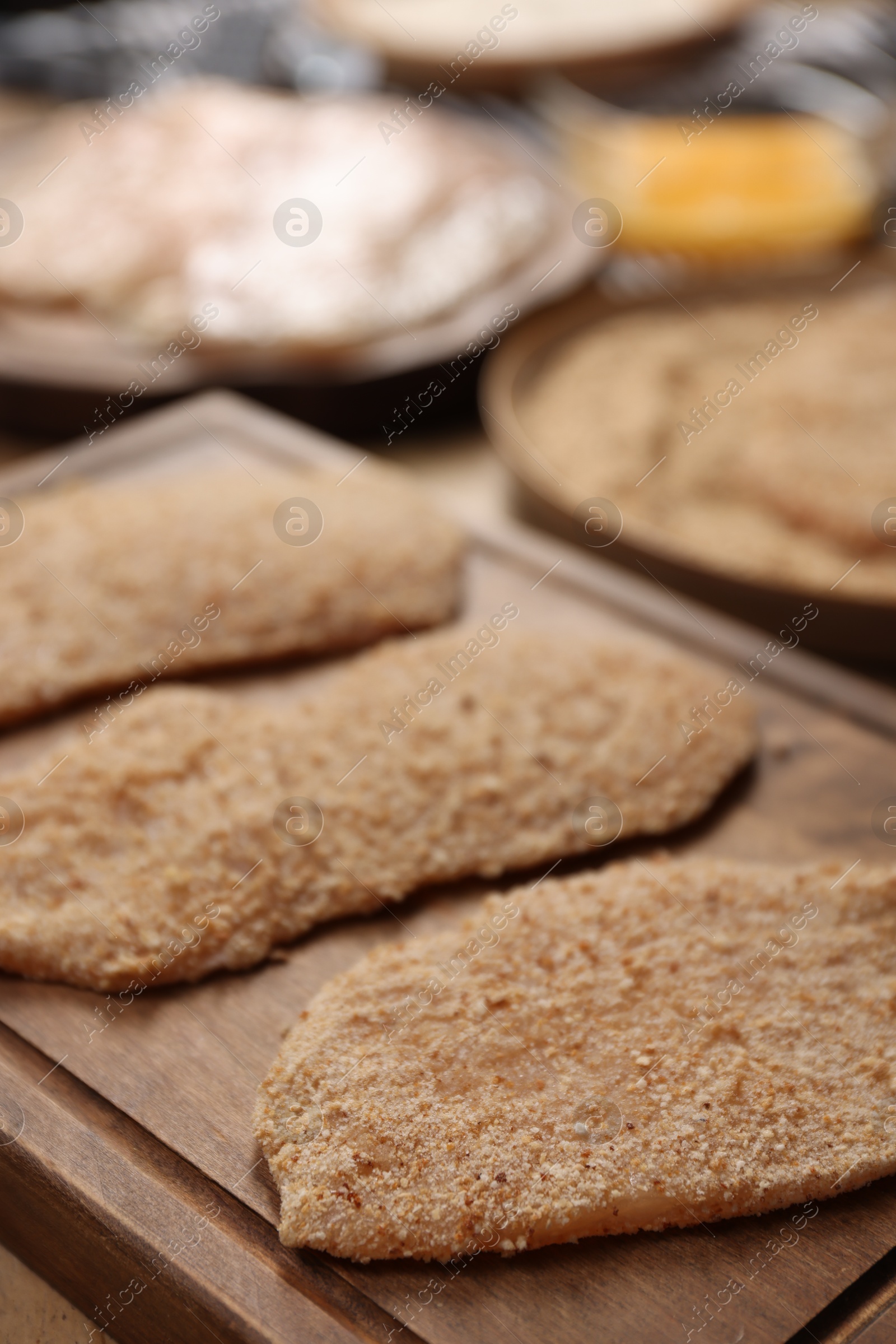 Photo of Making schnitzels. Raw meat and other ingredients on wooden table, closeup