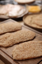 Photo of Making schnitzels. Raw meat and other ingredients on wooden table, closeup