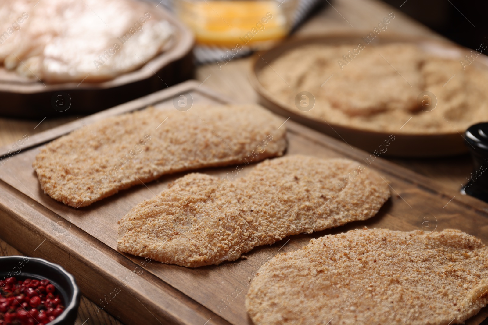 Photo of Making schnitzels. Raw meat and other ingredients on wooden table, closeup