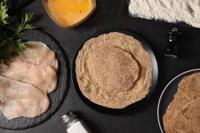 Making schnitzels. Raw meat and other ingredients on black table, flat lay