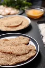 Making schnitzels. Raw meat and other ingredients on black table, closeup