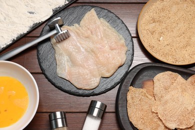 Photo of Making schnitzels. Raw meat and other ingredients on wooden table, flat lay