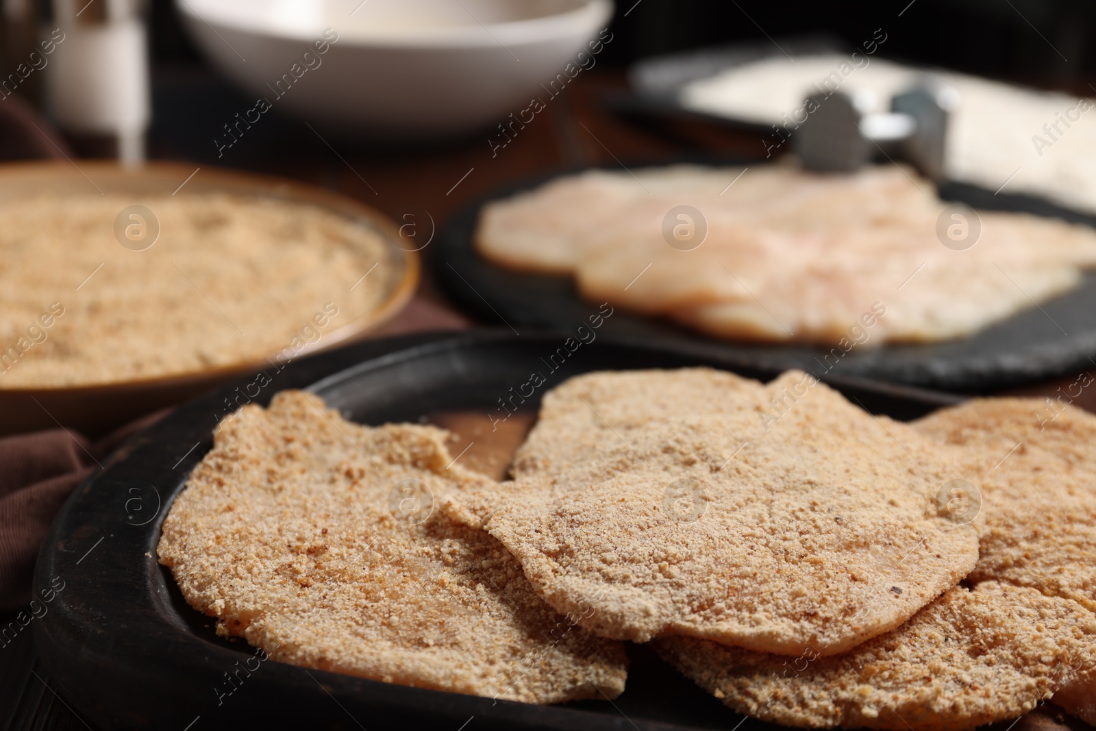 Photo of Making schnitzels. Raw meat and other ingredients on wooden table, closeup